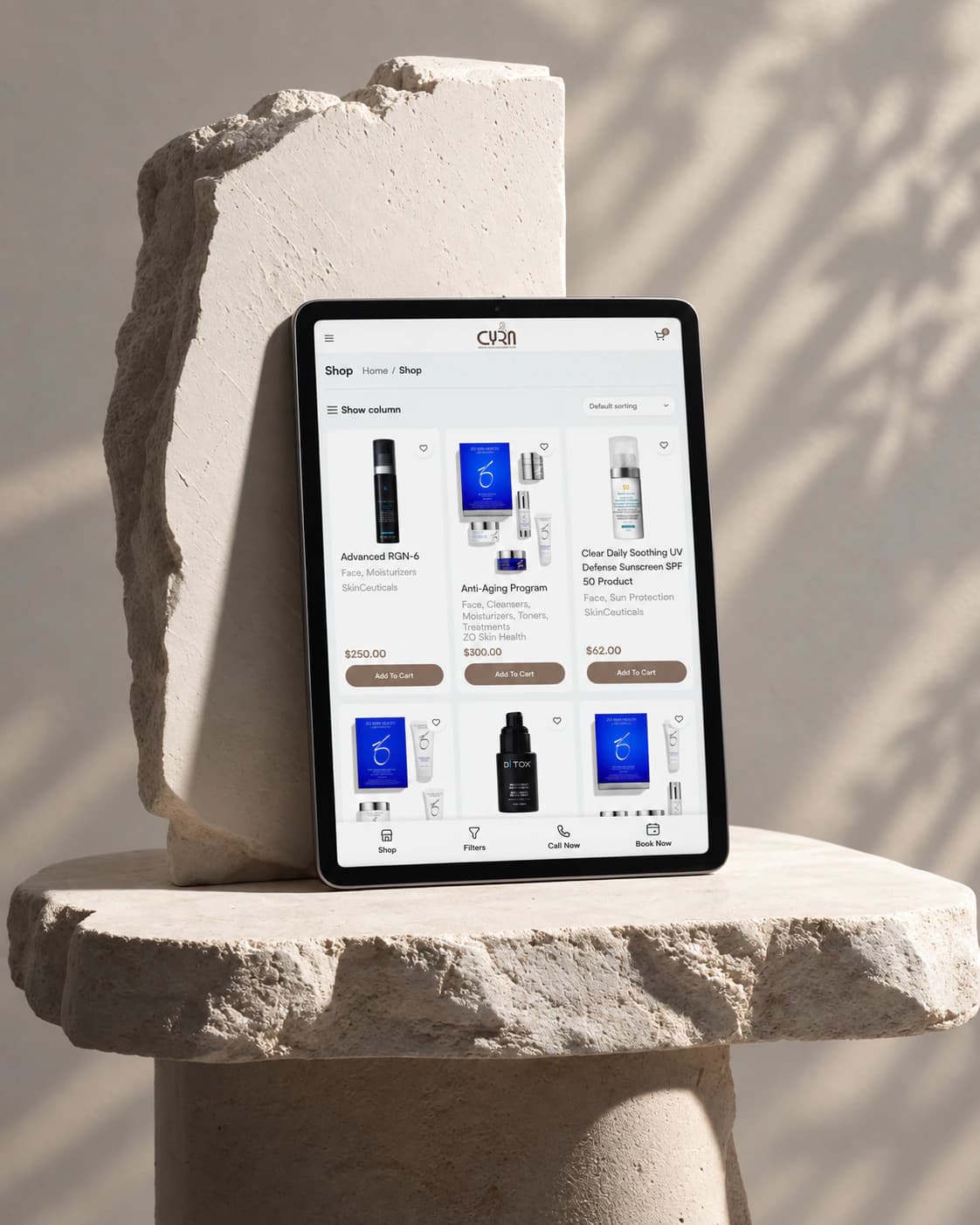 Cyra Beauty skincare shop page on a tablet, on a white stone block