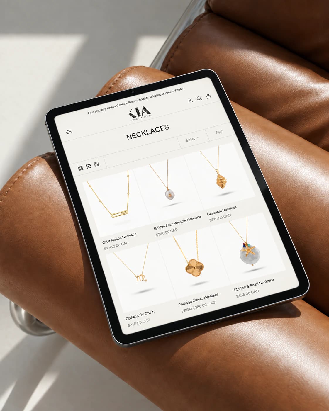 Kia Concept Store necklaces collection page on a tablet, resting on a cognac leather lounge chair