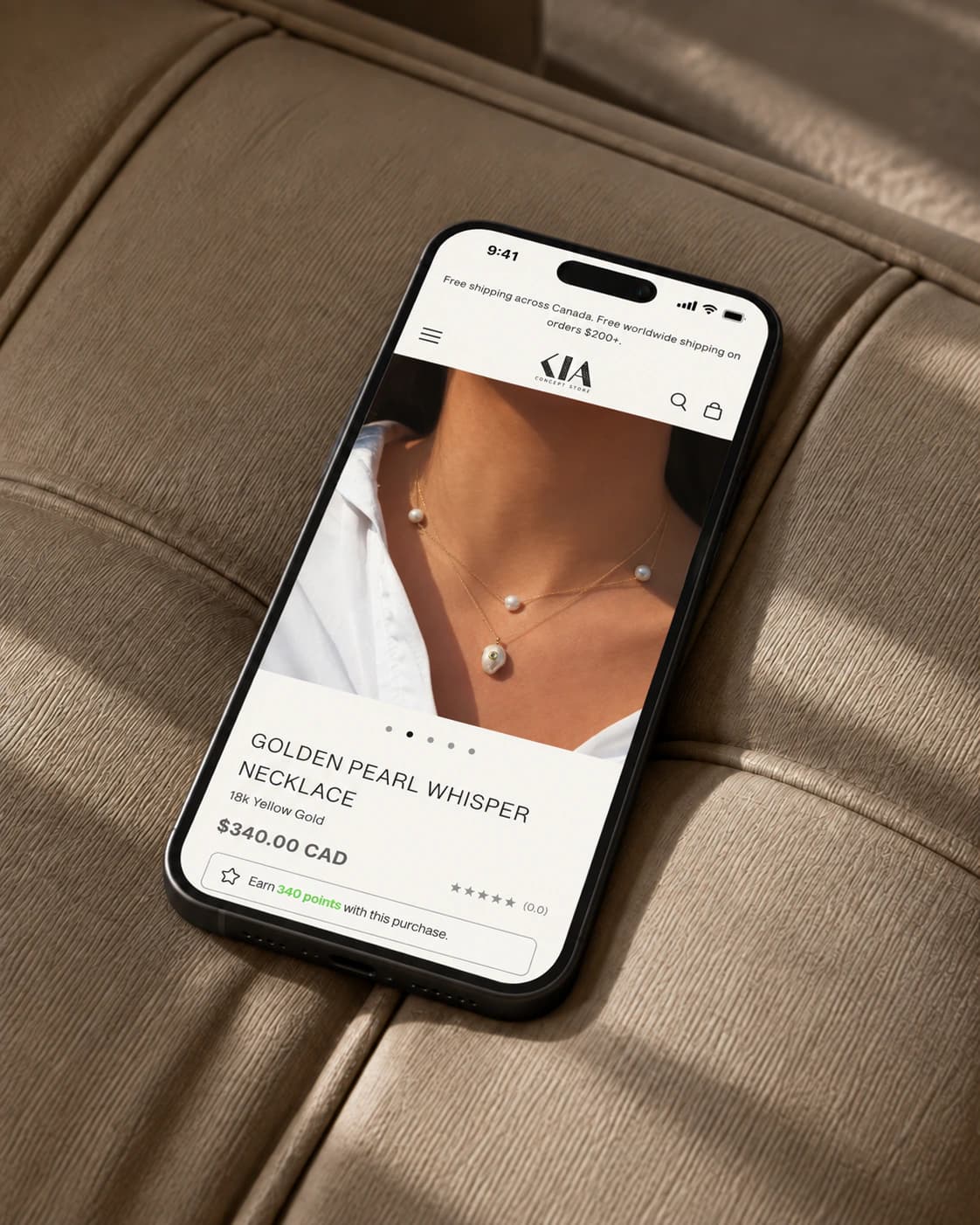 Kia Concept Store Golden Pearl Whisper necklace product page on a phone, on tailored leather