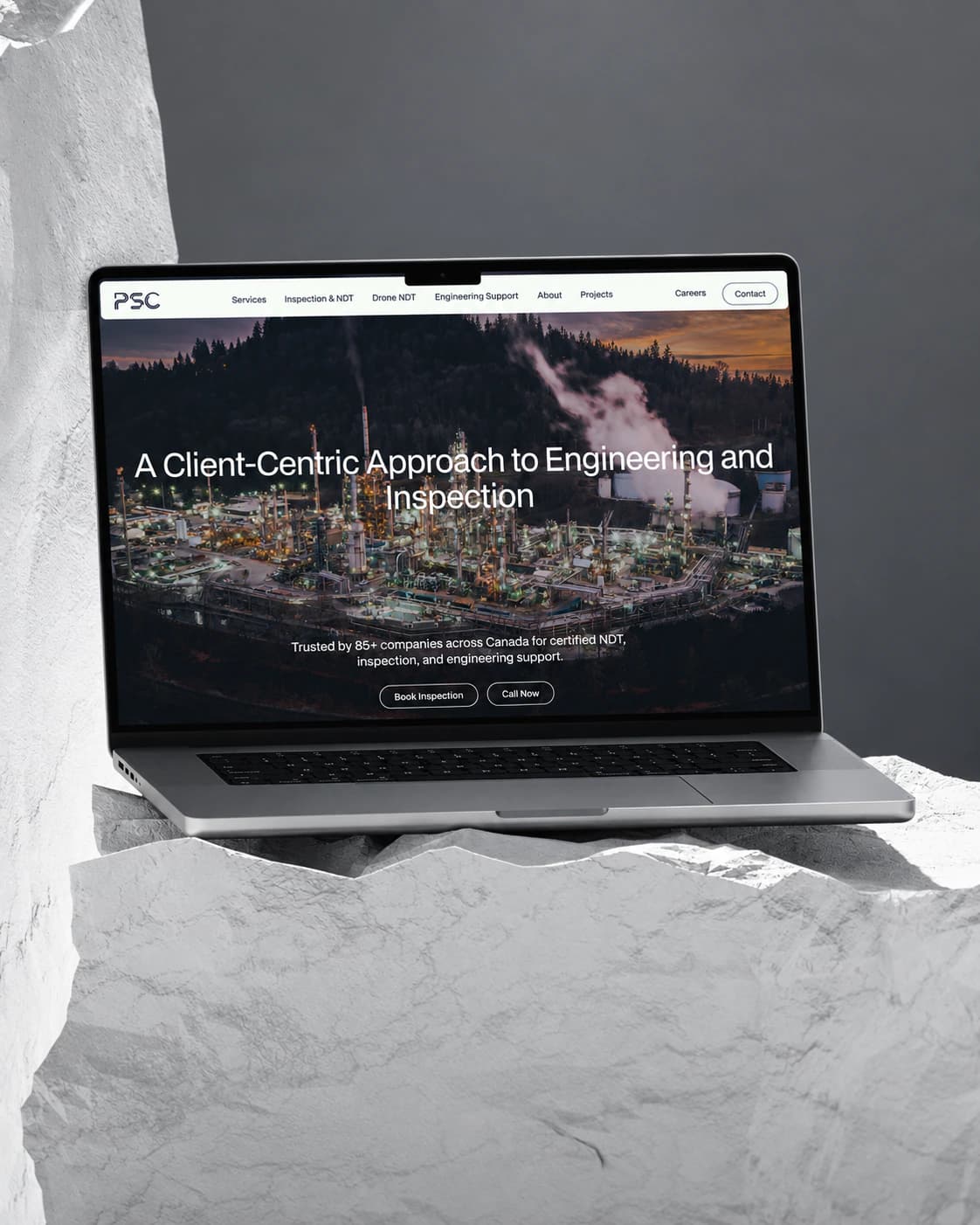 PSC inspection and engineering homepage on a laptop, set on a white rock