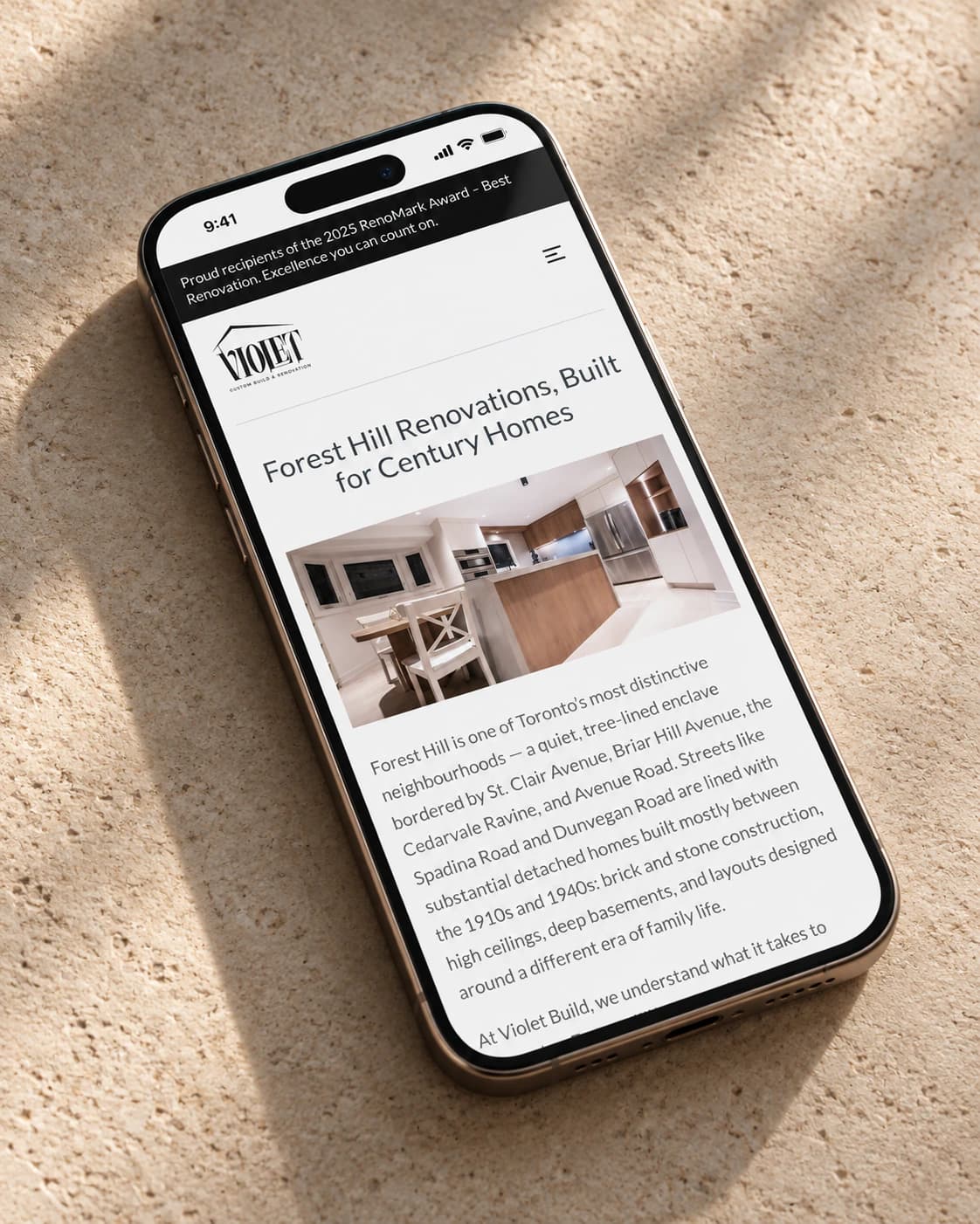 Violet Build Forest Hill renovations service page on a phone, laid on stone