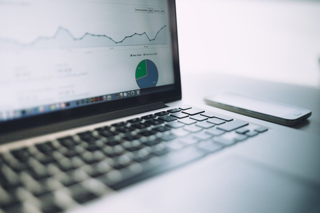 Laptop showing website traffic results in line and pie charts, beside a phone.