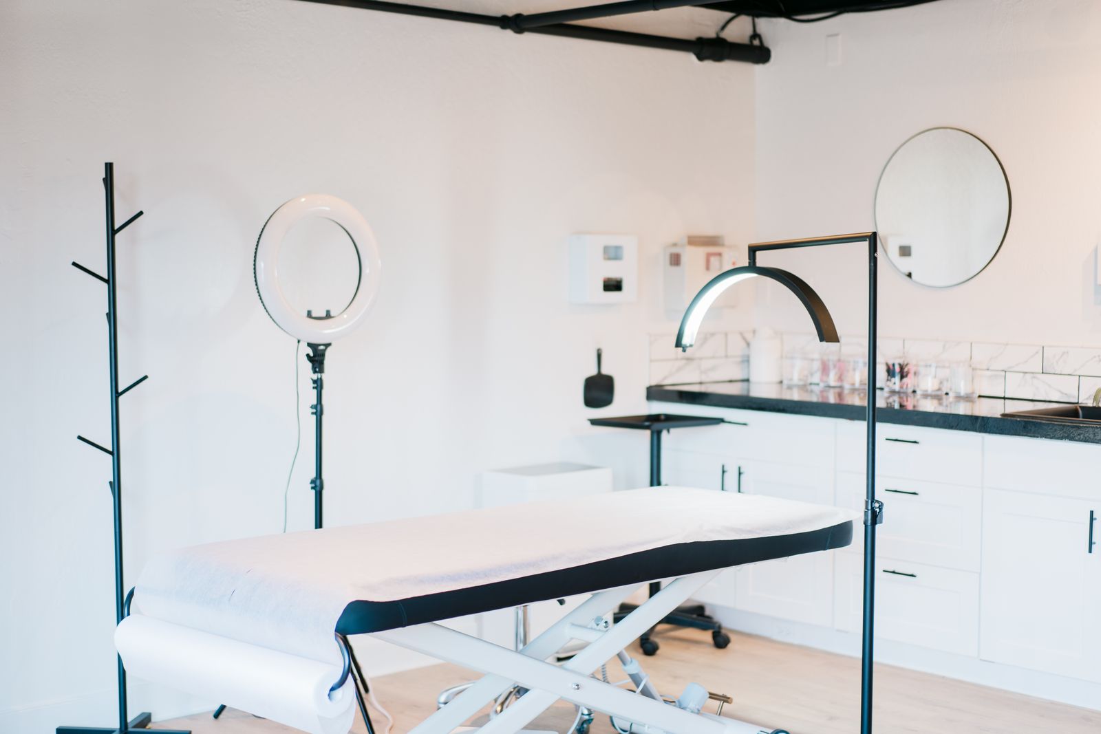 Bright, empty medspa treatment room with a massage bed and studio lighting — the room a membership program keeps booked.