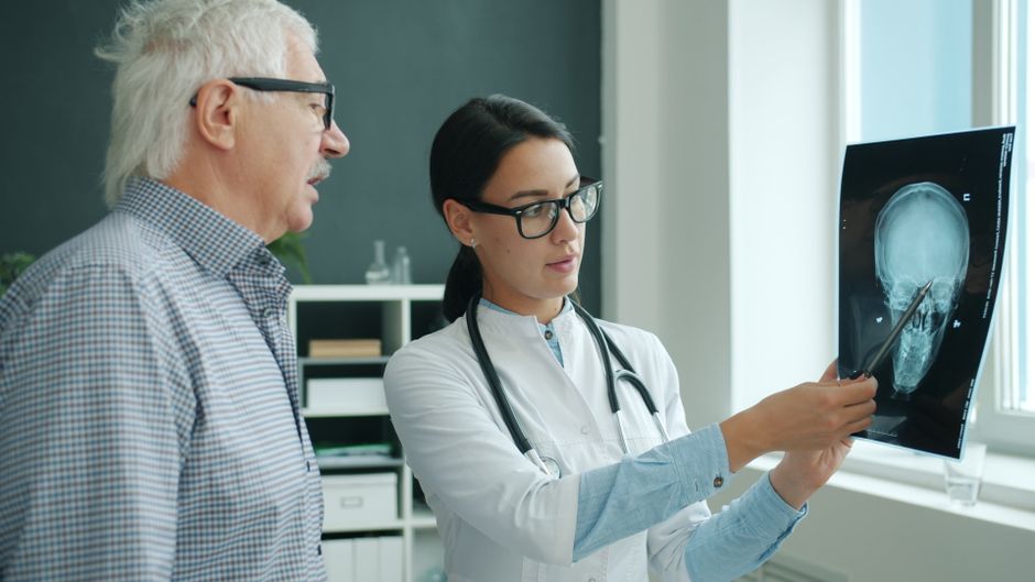 A doctor reviews a patient's head X-ray in a medical office, discussing the results.